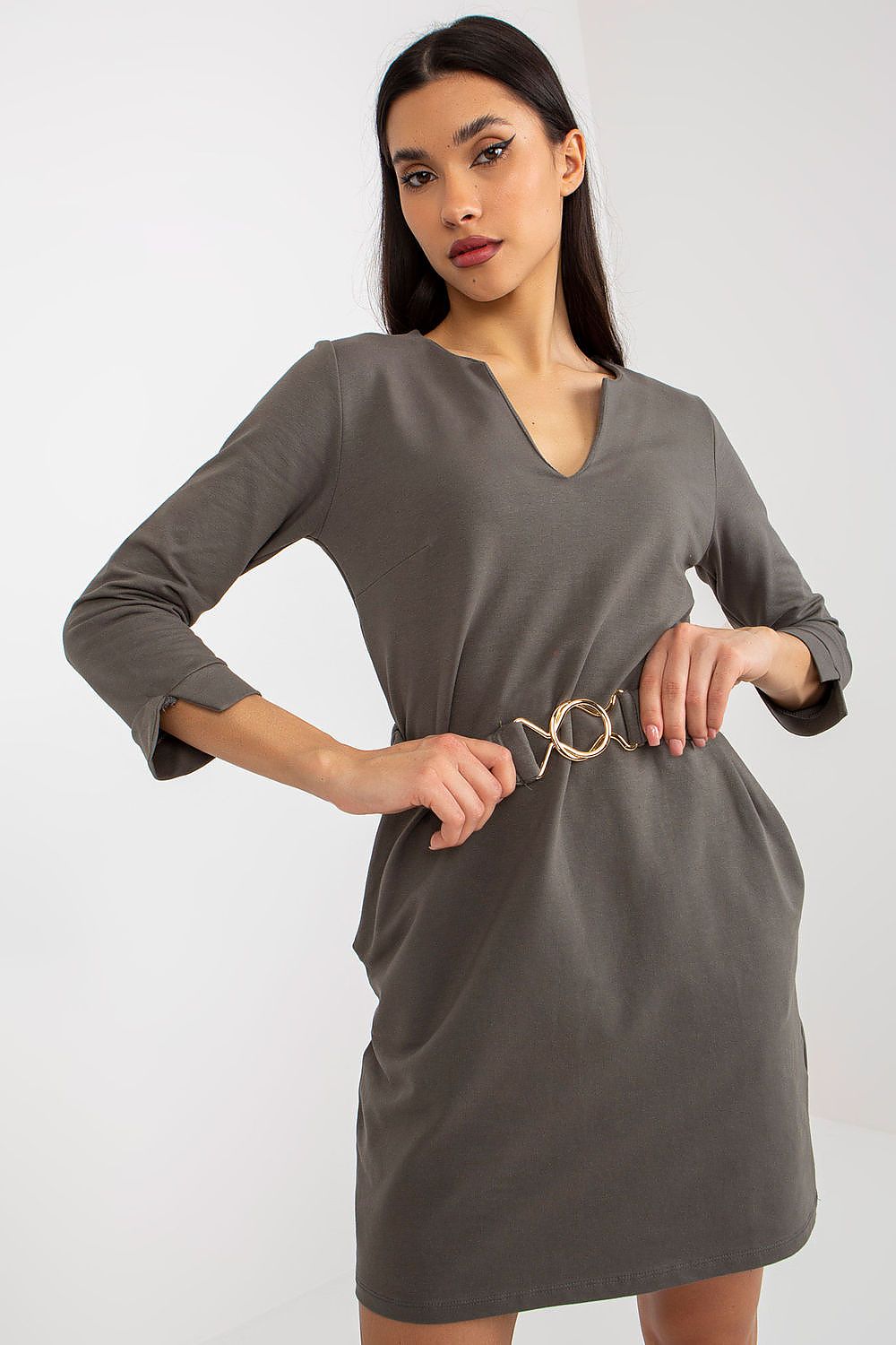 Woman wearing a gray dress with a belt on a white background