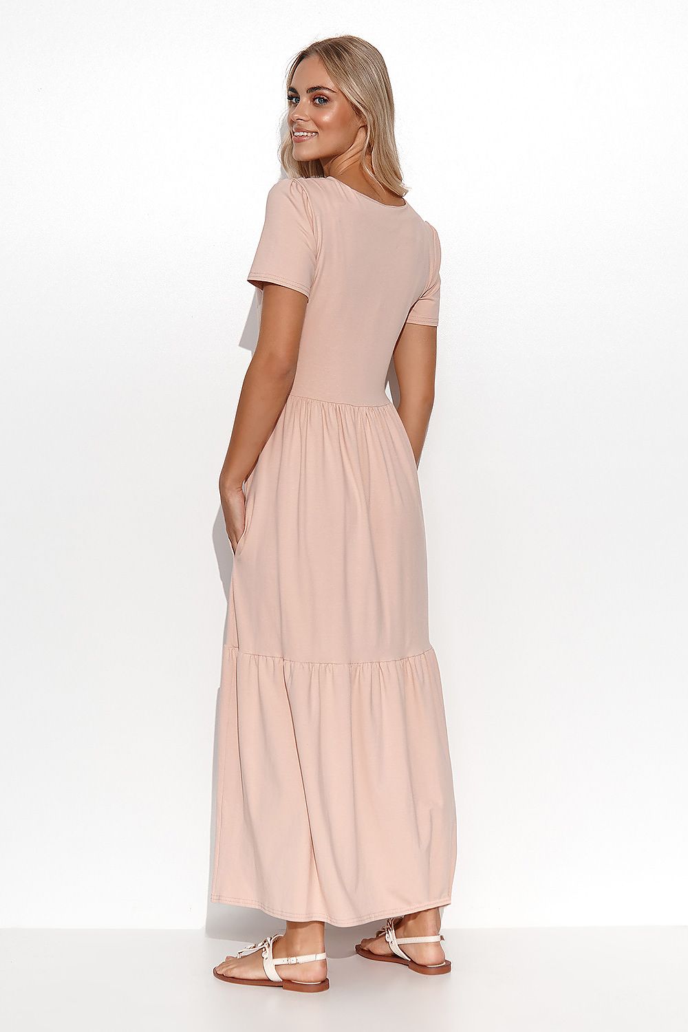 Woman wearing a long, light pink dress on a white background
