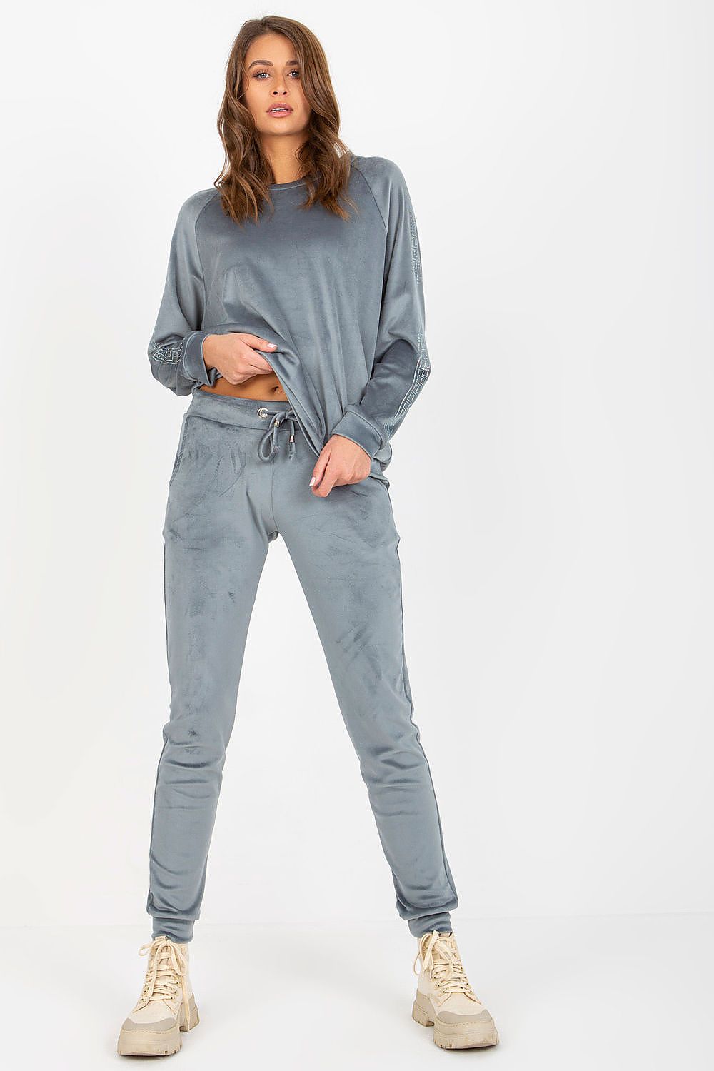 Woman wearing a gray sweatshirt and pants set on a white background