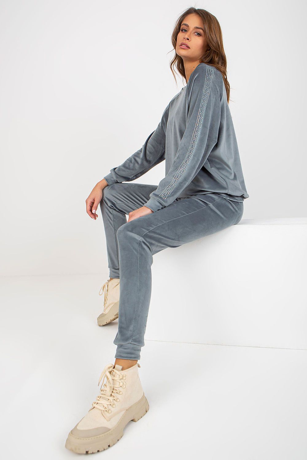 Woman wearing a gray tracksuit with beige shoes on a white background