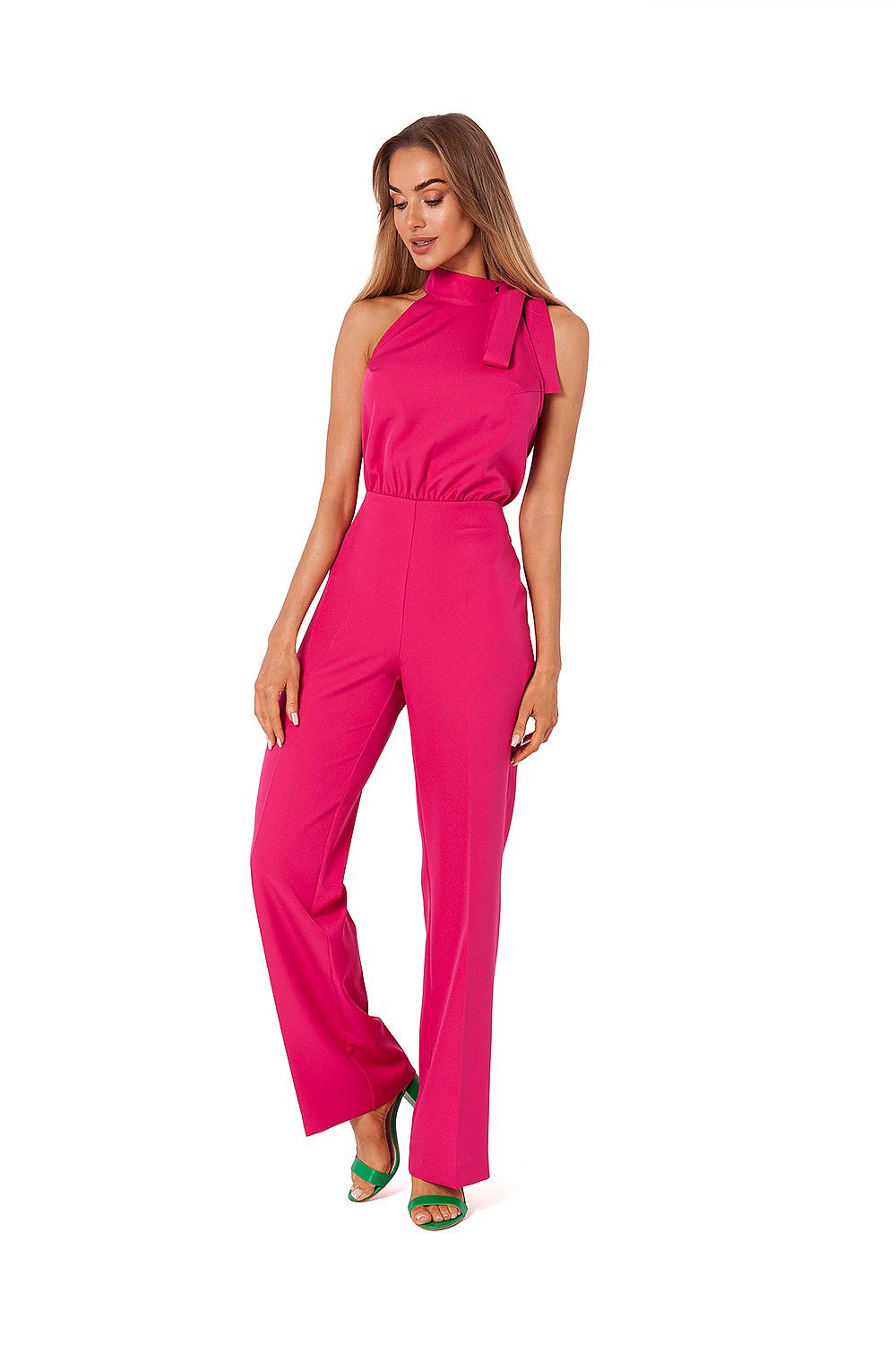 Woman wearing a bright pink jumpsuit on a white background