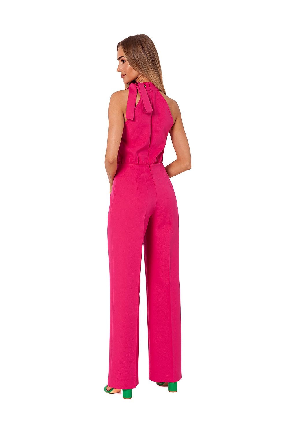 Woman wearing a bright pink jumpsuit with a bow detail on a white background