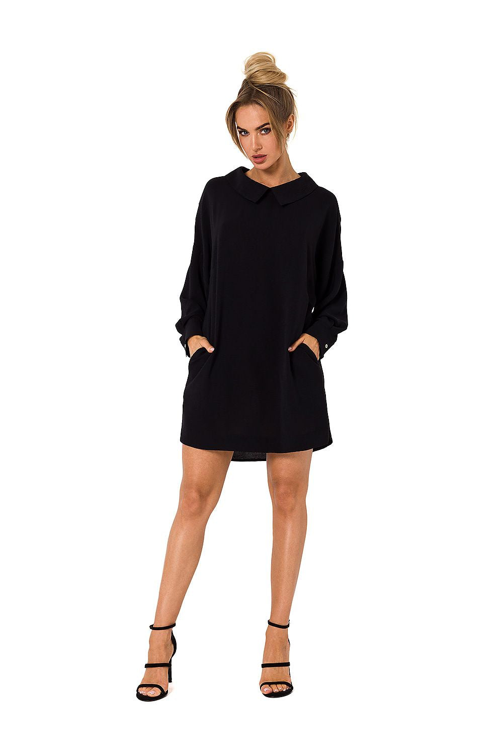 Woman wearing a black dress with long sleeves on a white background