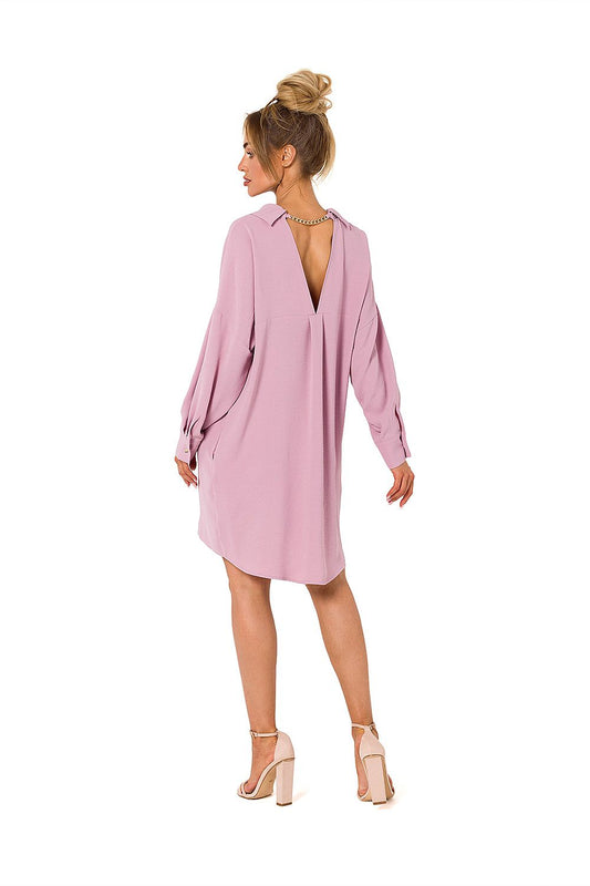 Woman wearing a pink dress with a backless design on a white background