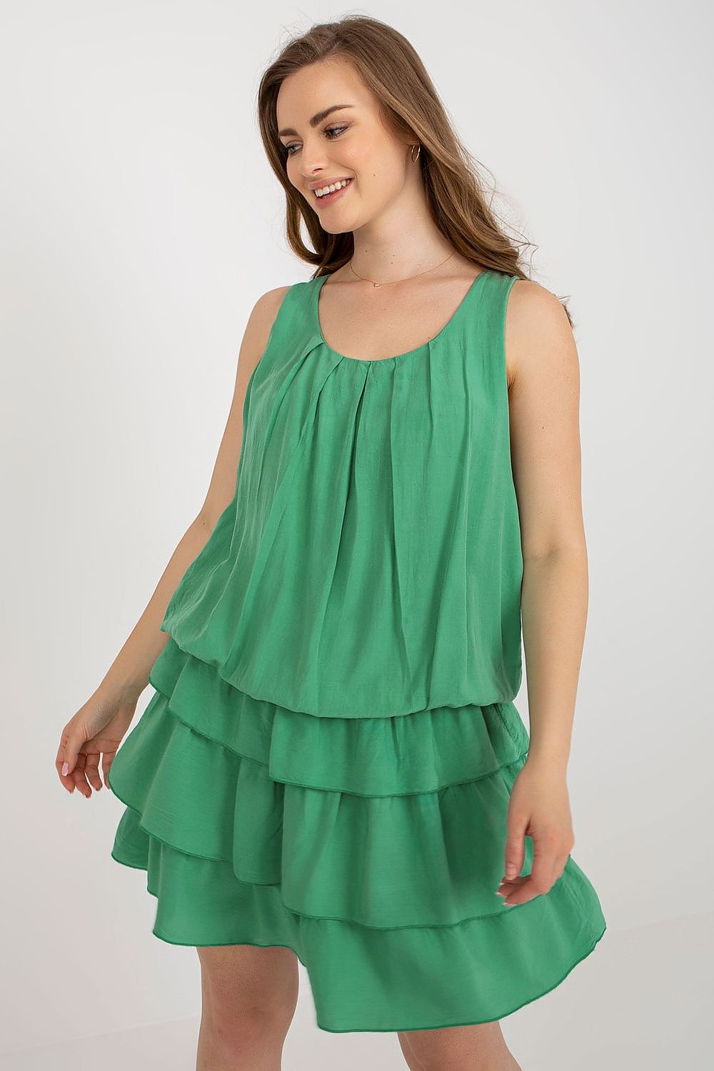 Woman wearing a green dress with ruffled layers on a white background