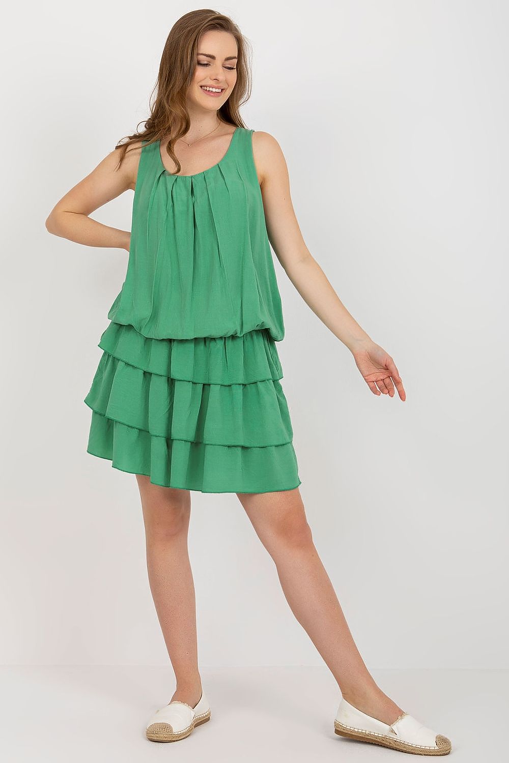 Woman wearing a green tiered dress on a white background