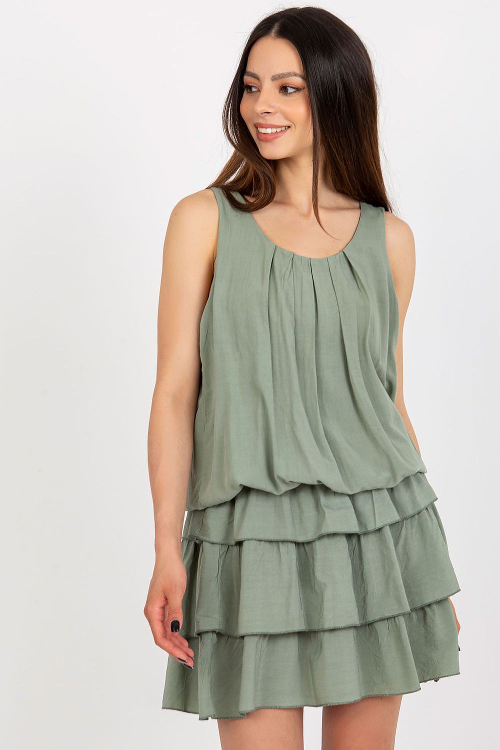 Woman wearing a green tiered dress on a white background