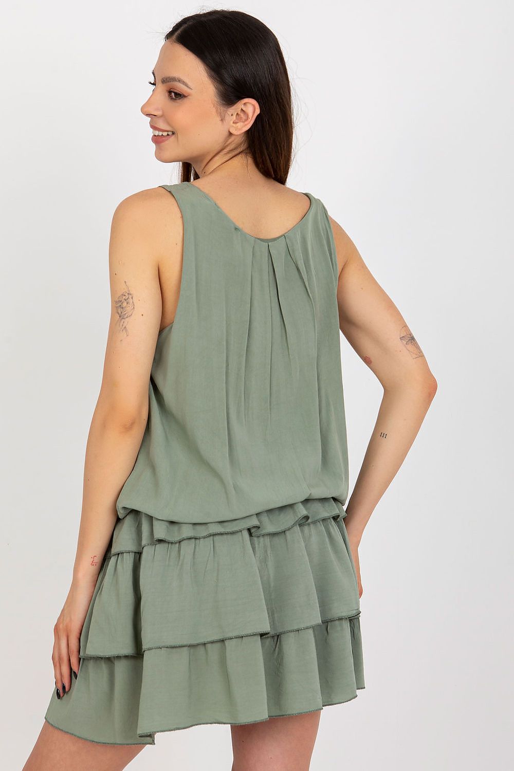 Woman wearing a green tiered dress on a white background