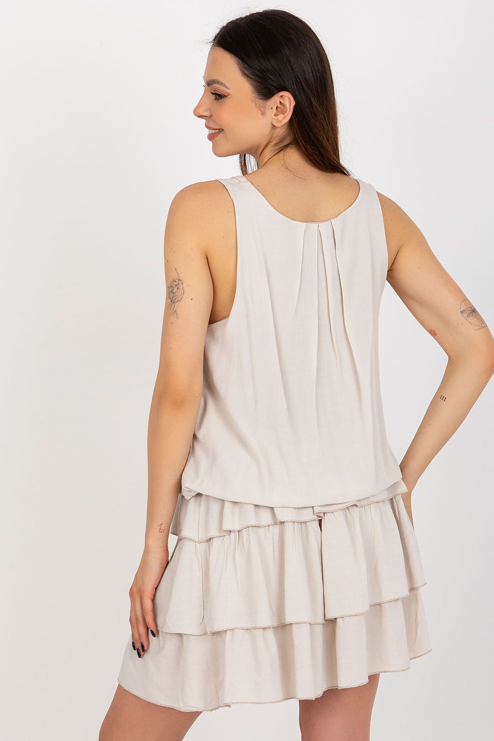 Woman wearing a beige layered dress against a white background