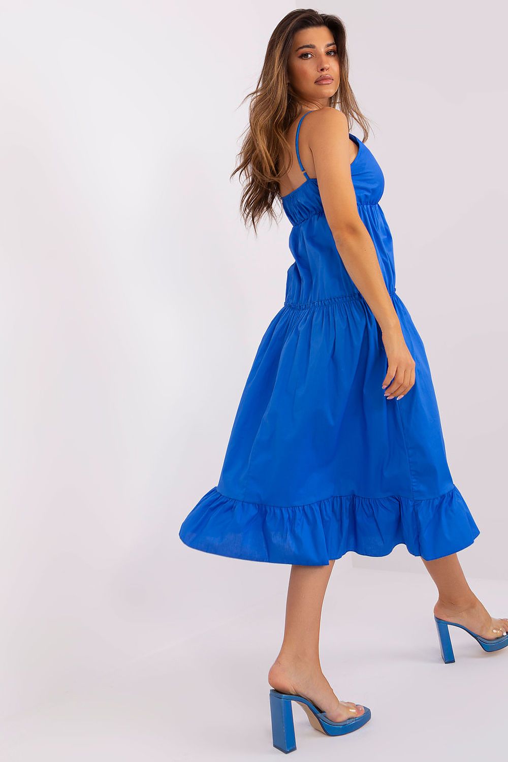 Woman wearing a blue dress with ruffled hem on a white background