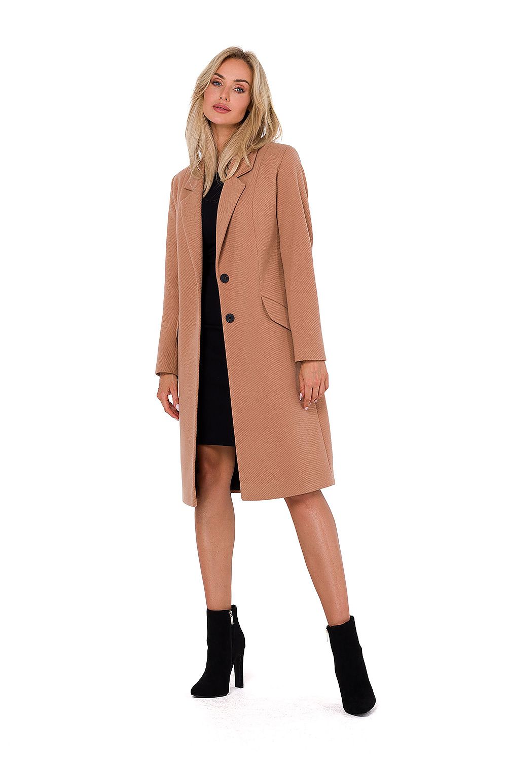 Woman wearing a tan coat over a black dress on a white background