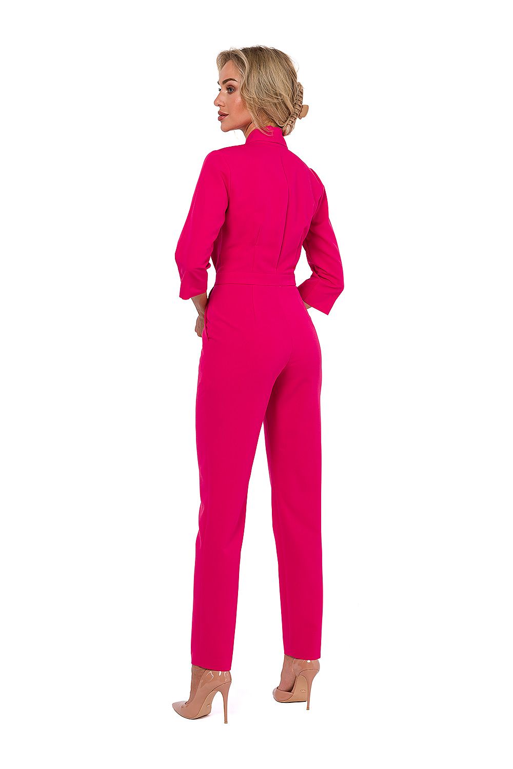 Woman wearing a bright pink jumpsuit on a white background