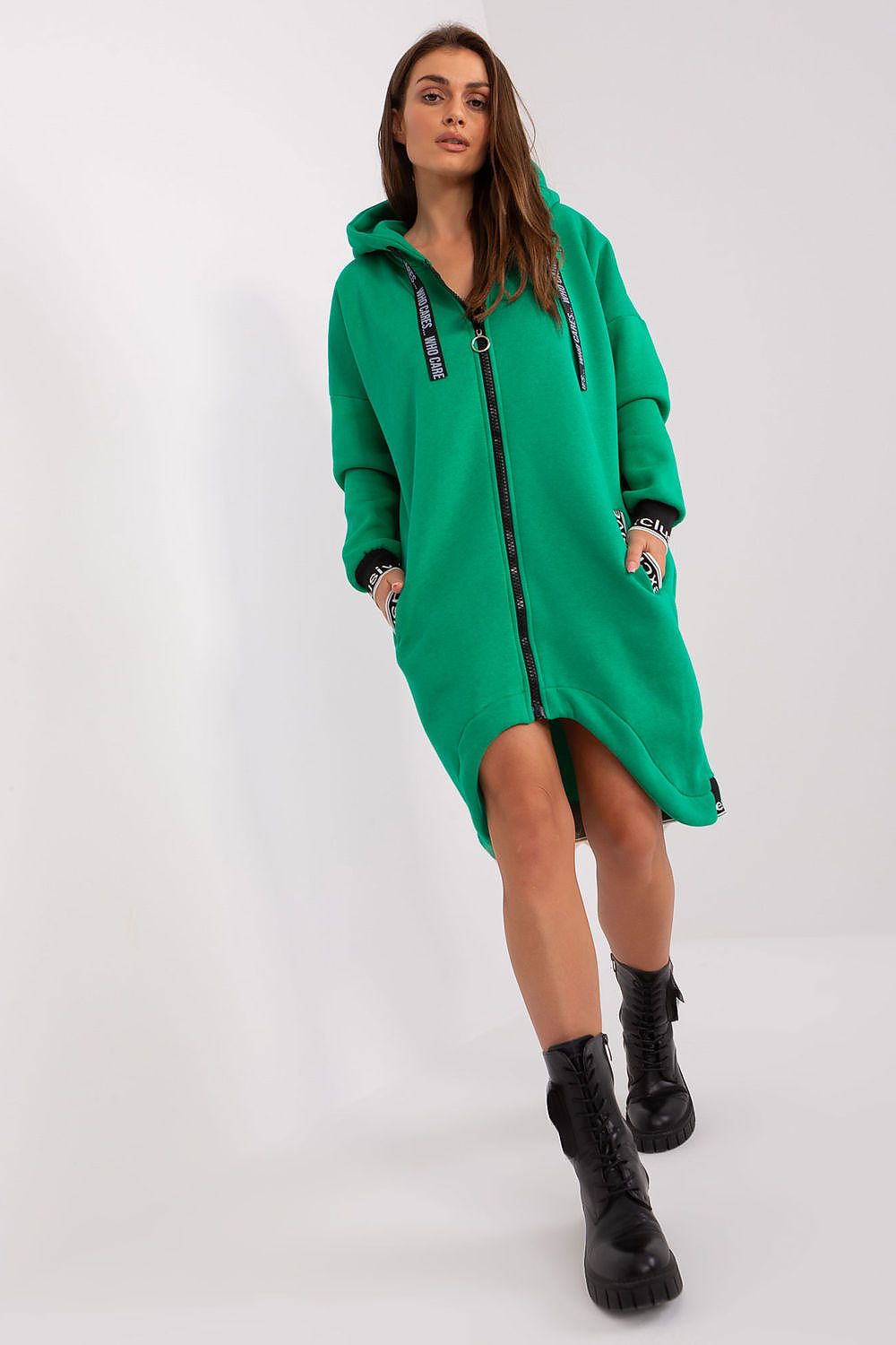 Woman wearing a green hoodie dress with black boots on a white background