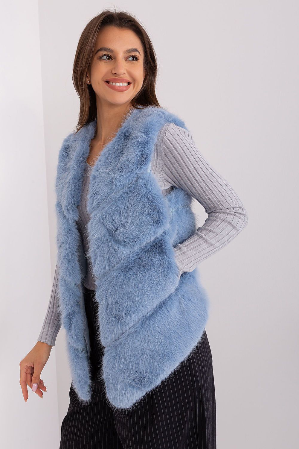 Woman wearing a light blue fur vest against a white background