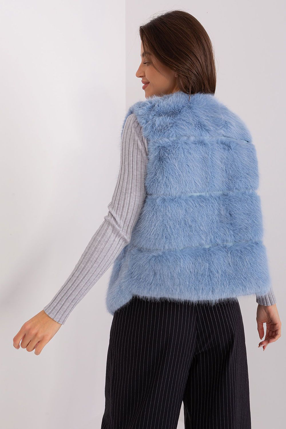 Woman wearing a light blue fluffy vest on a white background