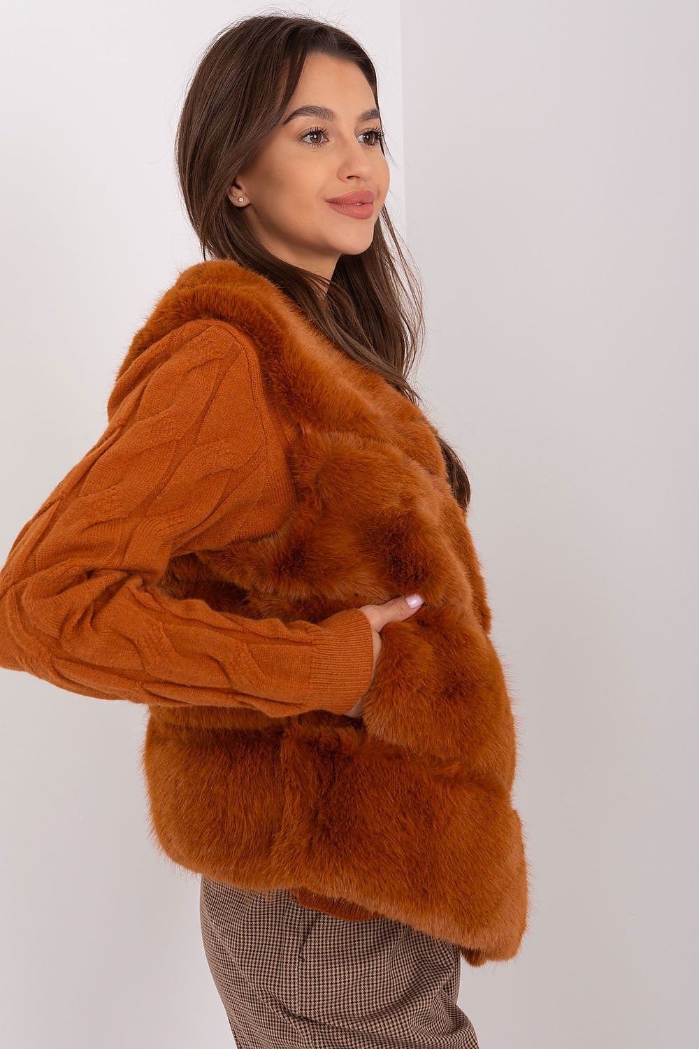 Woman wearing a brown faux fur jacket against a white background