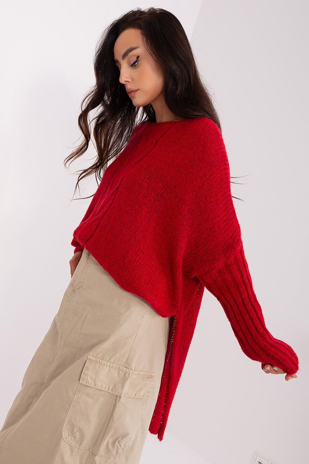 Woman wearing a red sweater and beige pants on a white background