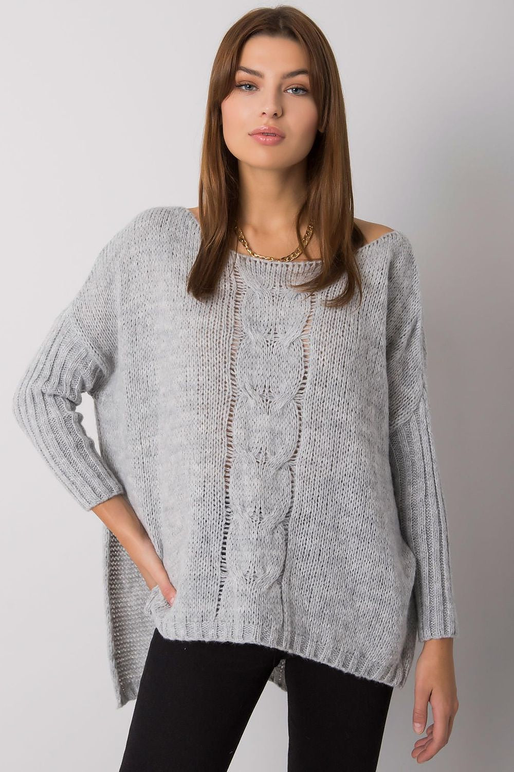 Woman wearing a gray knitted sweater against a plain background