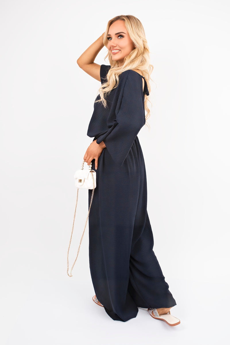 Navy: “Wide leg V-neck jumpsuit in navy with back tie detail, side view”